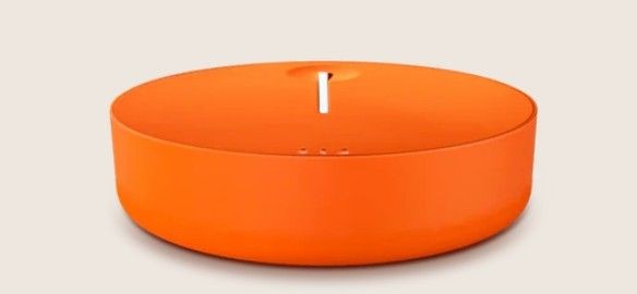 Orange modern piggy bank with a coin slot on top against a neutral background.